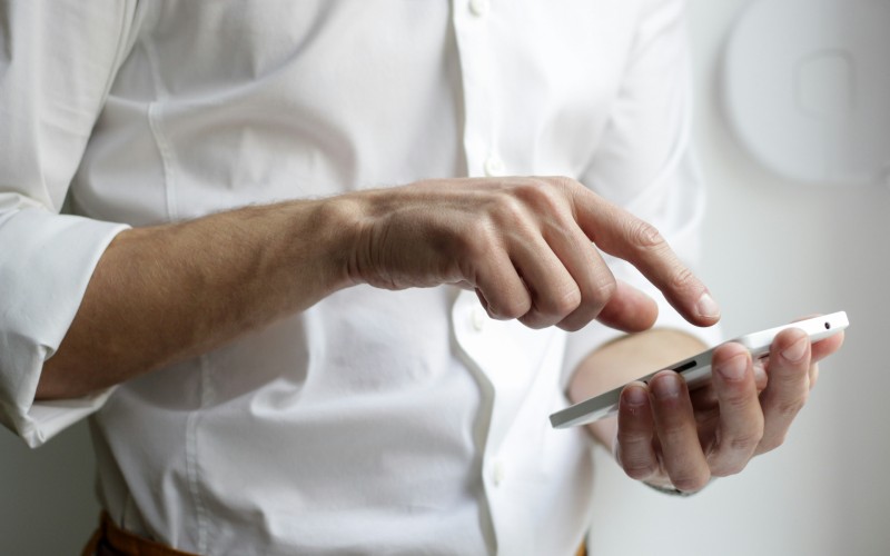 person holding white Android smartphone in white shirt. Credit: NordWood Themes, Unsplash