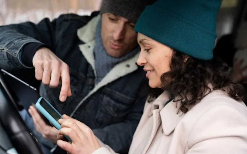 Man and woman look at phone in car
