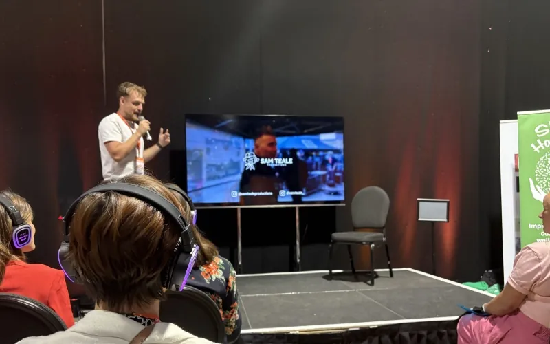 Sam Teale speaks to a fully-headphoned crowd at Climb 25